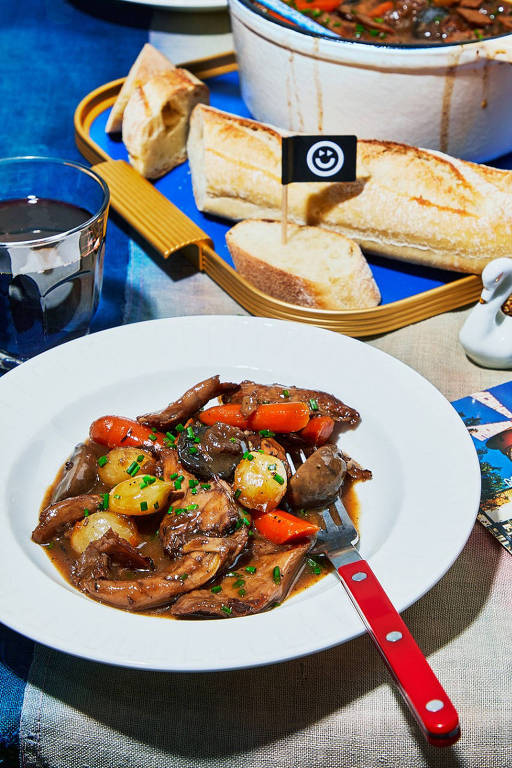 A foto mostra um prato branco com Coq au vin vegano, clássica receita francês do "galo ao vinho" feito com frango vegano