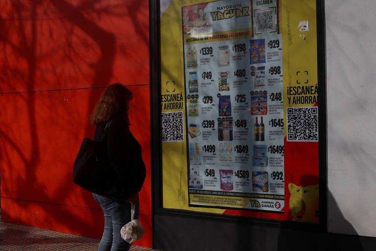 Mulher olha preços de produtos ao lado de fora de mercado em Buenos Aires