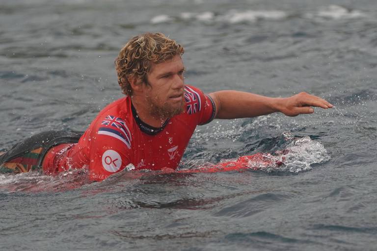 John John Florence deitado em sua prancha de surfe