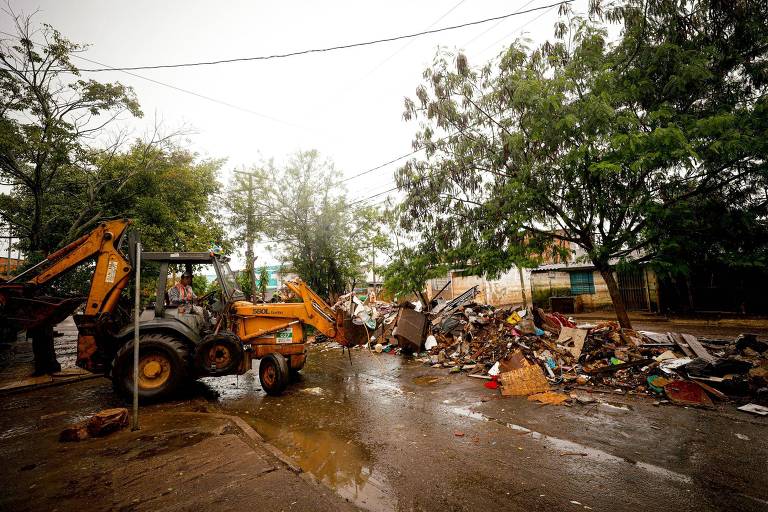 Máquina amarela faz recolhimento de lixo que se concentra no lado direito da imagem