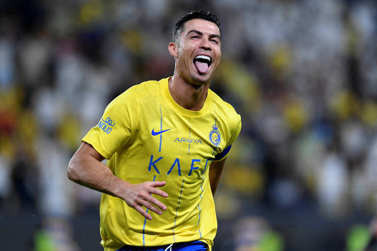 Usando camisa amarela, sorrindo e mostrando a língua, o português Cristiano Ronaldo, jogador mais bem pago do mundo, comemora gol pelo Al Nassr no Campeonato Saudita