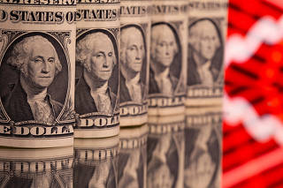 FILE PHOTO: U.S. one dollar banknotes are seen in front of displayed stock graph