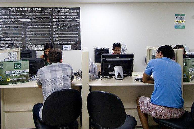 Pessoas sendo atendidas em cartório de registro civil
