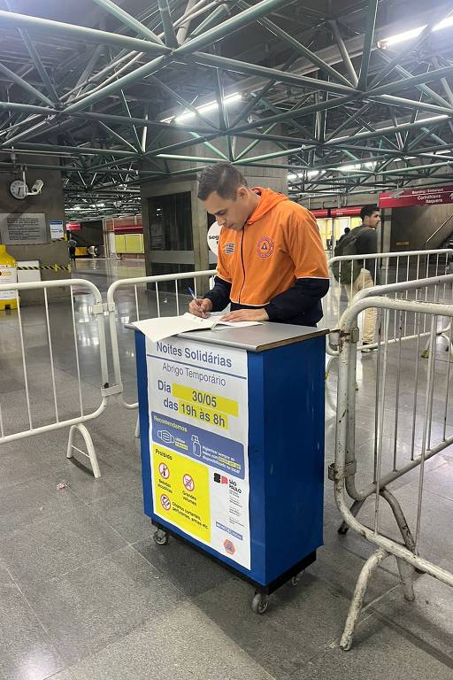 Funcionário da Defesa Civil do Estado de São Paulo aguarda a abertura do abrigo solidário na estação Pedro 2º do metrô, no centro de São Paulo, para atender os moradores em situação de rua durante o frio intenso