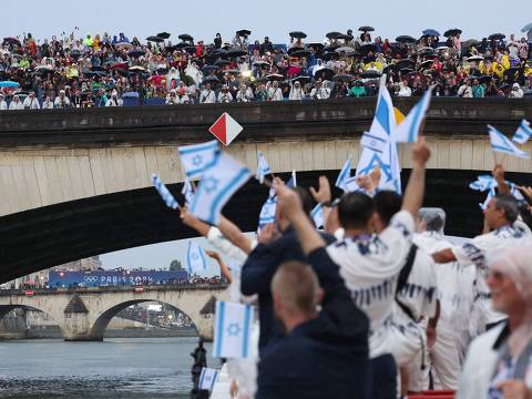 Paris 2024 Olympics - Opening Ceremony - Paris, France - July 26, 2024. Spectators in a stand on a bridge over the river Seine look on at athletes of Israel aboard a boat in the floating parade on the river Seine during the opening ceremony. (Photo by Nir Elias / POOL / AFP)