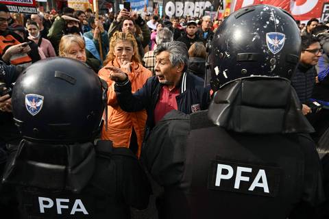 A man argues with riot police officers during a protest outside the National Congress in Buenos Aires on September 11, 2024. Argentina's Chamber of Deputies is debating on September 11, whether to reverse a veto by President Javier Milei of a law to increase pensions. (Photo by Luis ROBAYO / AFP)