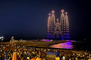 Locals and tourists look at 300 drones lighting the sky, creating an image of the Sagrada Familia Basilica, by Flock Drone Art, in Barcelona