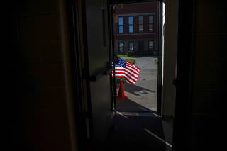 A U.S. flag blows in the doorway of a polling station in Columbus, Ohio, Nov. 3, 2020. (Maddie McGarvey/The New York Times)