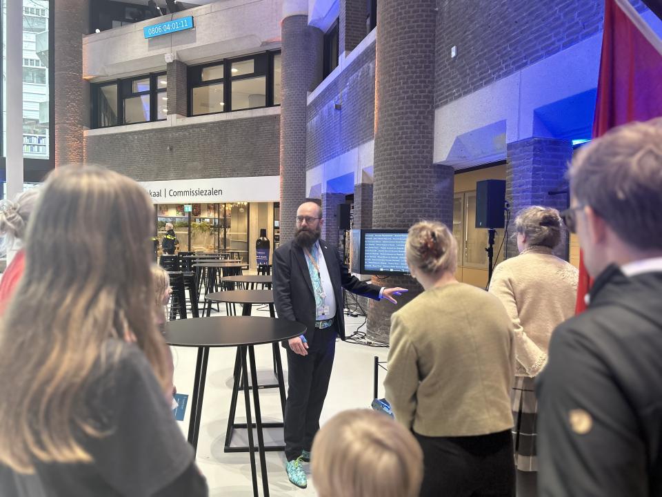 Een groep mensen op de rug gezien luistert naar Wouter Verheijden, die iets aan hen uitlegt.