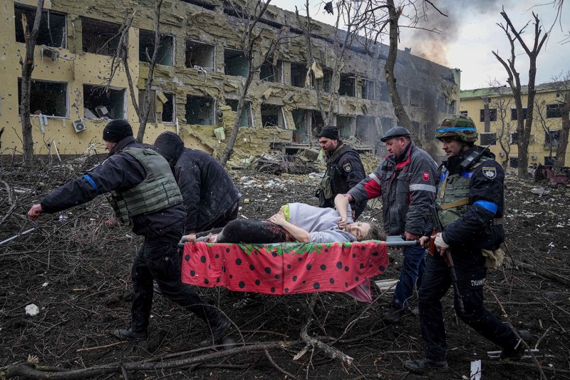 Ukrainian emergency employees and volunteers carry an injured pregnant woman.