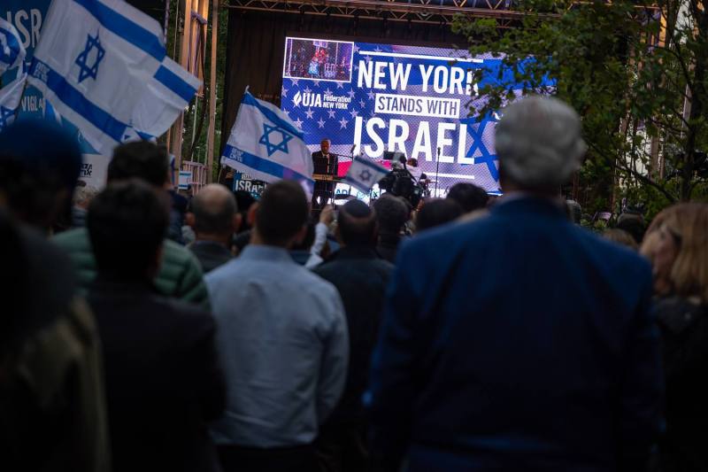 Demonstrators carry Israeli flags and a large sign that reads "New York Stands With Israel."