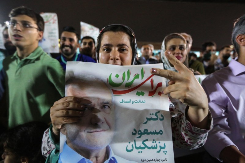 Supporters of reformist Iranian presidential candidate Massoud Pezeshkian lift his portraits during a rally in Tehran on June 26.