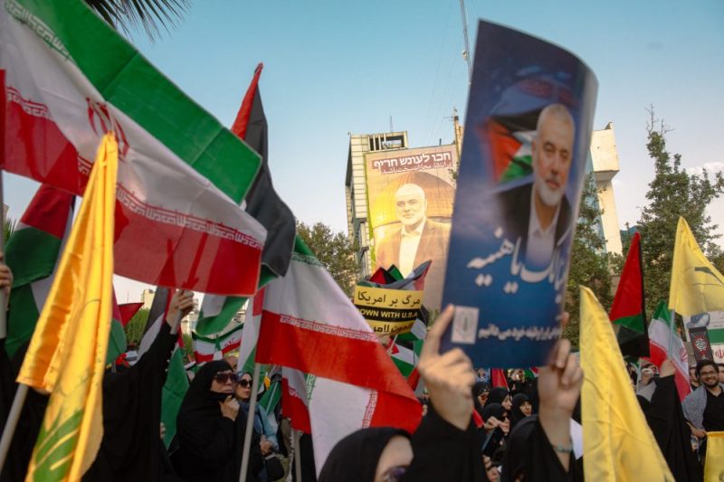 Iranians wave national flags and hold photos of slain Hamas political leader Ismail Haniyeh in Tehran on July 31.