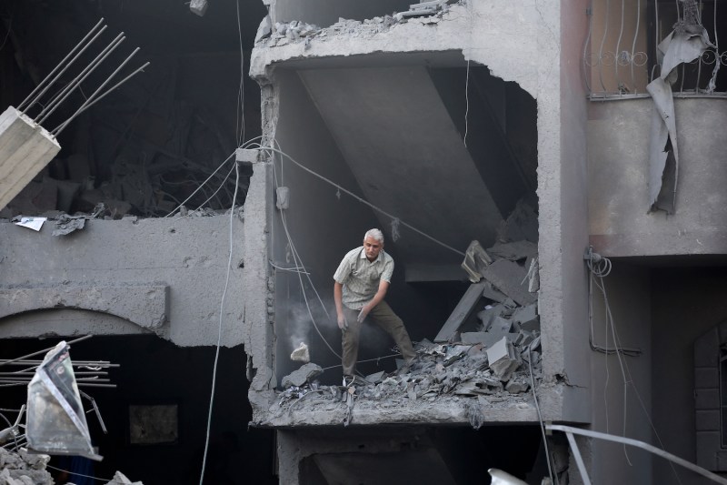 A man clears rubble from a building hit during Israeli bombardment in Nuseirat, in the central Gaza Strip.