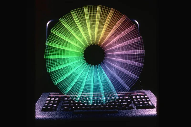 A spinning color wheel is superimposed over the keyboard and screen of a supercomputer.