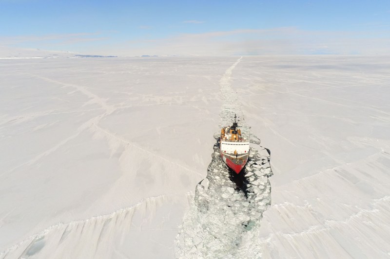 A ship is seen cutting through a fast icy landscape.