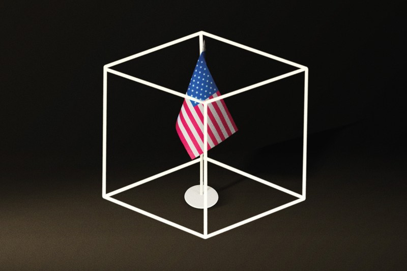 An illustration shows a US flag on a stand inside of the wire frames of a cube box.