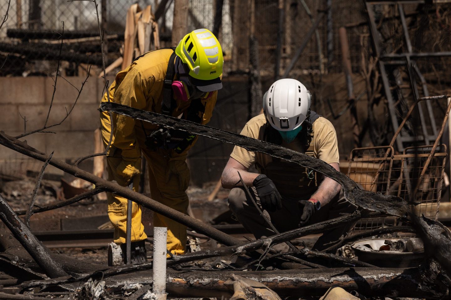 Search and recovery team members check charred buildings and cars in the aftermath of the Maui wildfires in Lahaina, Hawaii, on August 18, 2023. At least 111 people are known to have died in what was the deadliest wildfire in the US in over a century. The final toll is expected to be considerably higher. (Photo by Yuki IWAMURA / AFP) (Photo by YUKI IWAMURA/AFP via Getty Images)