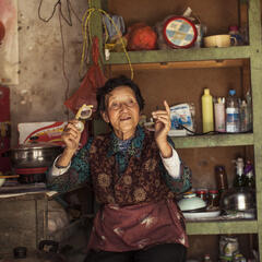 Older Tibetan woman sits in her living room in China.