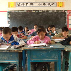 Middle school kids work at desks in a run down classroom in rural China.