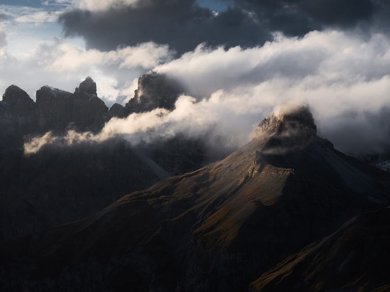 Clouds billowing over sun-kissed mountain peaks