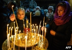 People light candles during Christmas midnight Mass at Moscow's Cathedral of Christ the Savior on January 6.