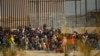移民游过美墨边境的格兰德河后在边境隔离墙前聚集。（2023年12月18日）