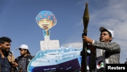 胡塞武装支持者举着火箭筒以及被胡塞武装扣押的货船的图像在也门首都萨那游行。(2024年2月7日)