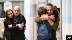 2024年2月12日，在以色列拉马特甘的舍巴医疗中心，被营救的人质费尔南多·马尔曼（右）和路易斯·哈尔（左二）拥抱亲人。（美联社照片）