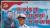 资料照：一名中国解放军海军士兵在香港的海军基地站在有着中国领导人习近平画像的宣传标语前。（2016年7月8日）