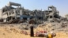 在加沙市西部的斯纳居民区，在以色列军队从该地段撤走后，一名拾捡物件的妇女环视联合国近东巴勒斯坦难民救济和工程处的院落废墟。(2024年7月12日)
