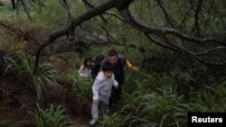 资料照：一家来自中国的移民渡过美墨边境的格兰德河正在走出美国德克萨斯州的丛林。（2023年4月4日）