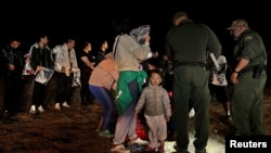 资料照片：一名两岁的中国幼童跟随他的家人渡过美墨边境的格兰德河进入美国德克萨斯州，这家人正在美国边境巡逻人员那里登记以便进入移民程序。（2023年3月23日）
