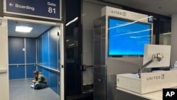 一名旅客坐在洛杉矶国际机场的登机通道内等待飞往杜勒斯国际机场的美国联合航空公司航班。微软系统故障导致美国航班大面积取消和延误。(2024年7月19日)