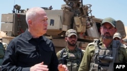 资料照片：2024年5月7日，以色列国防部长约阿夫·加兰特 在访问以色列南部拉法附近与加沙地带接壤的边境阵地时，与士兵站在自行火炮榴弹炮旁。（法新社照片）