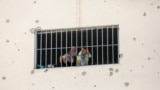 (FILE) Displaced Palestinians who fled their houses due to Israeli strikes look out from a window as they take shelter, in Khan Younis in the southern Gaza Strip, July 24, 2024.