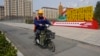 中国河北雄安街头一名工人骑车路过一处口号宣传牌 (2023年4月1日)