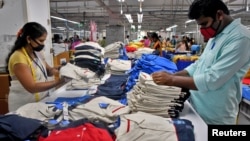 资料照片: 2022年2月9日印度一家纺织厂工人在包装T 恤前进行质量检查