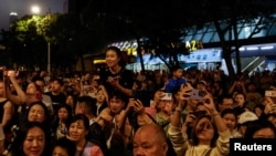 游客们在香港维多利亚港观看五一节的烟花。（2024年5月1日）