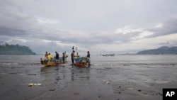 资料图片：喀麦隆林贝海滩，当地渔民在船上准备渔网。（2022年4月12日）