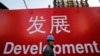 资料照：一名工人走过北京一处建筑工地的宣传标语。（2014年12月12日）