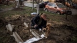 乌克兰布查镇一名男子在埋葬被俄军杀死的朋友后在墓旁悲泣。（2022年4月6日）