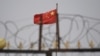 资料照：中国新疆喀什南部一处住宅区墙上的铁丝网与中国国旗。（2019年6月4日）