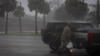 Un homme marche sous la pluie avec des sacs de provisions alors que l'ouragan Helene s'intensifie à Apalachicola, Floride, États-Unis, le 26 septembre 2024. 