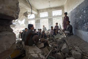 Children sit in a former classroom in a destroyed school in Saada City, Yemen. They now attend school in nearby UNICEF tents.