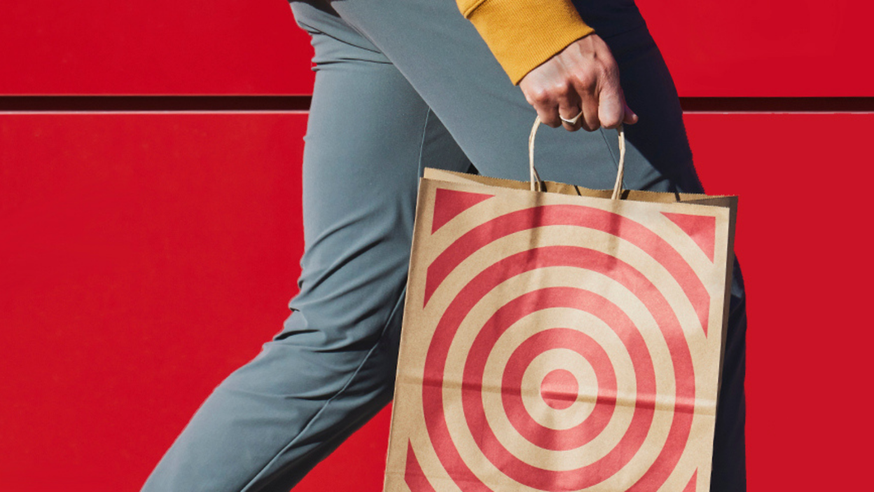 A person carrying a paper Target shopping bag against a red wall