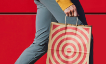 A person carrying a paper Target shopping bag against a red wall