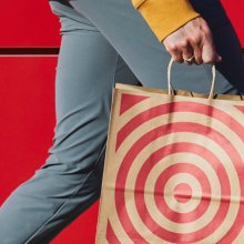 A person carrying a paper Target shopping bag against a red wall