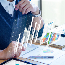 man sitting at desk looking at papers and graphs