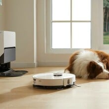 a roborock robot vacuum cleans the floor in front of a sleeping dog